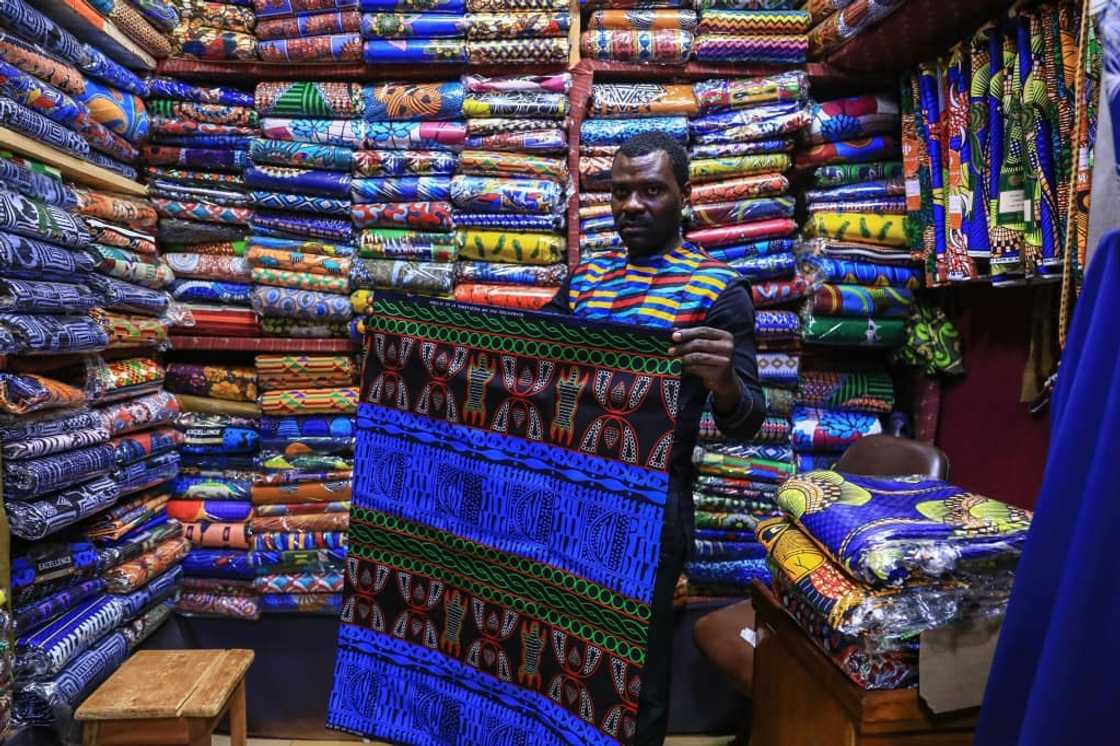 Iridescent: A trader holds a piece of the bright blue ndop ceremonial cloth in Bafoussam market in Cameroon Iridescent: A trader holds a piece of the bright blue ndop ceremonial cloth in Bafoussam market in Cameroon