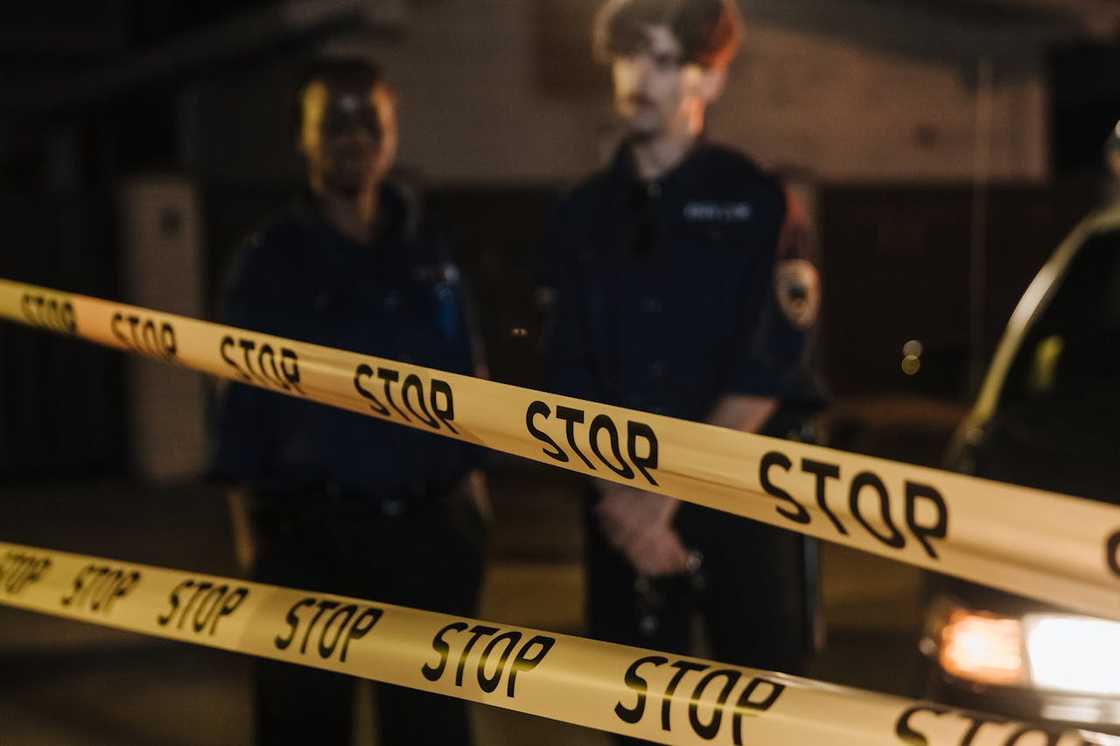 A police barrier blocks a street while officers stand behind it. A police barrier blocks a street while officers stand behind it.