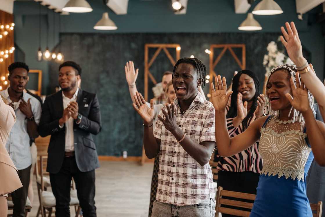 A group of people worshipping indoors, clapping and singing during a church service.