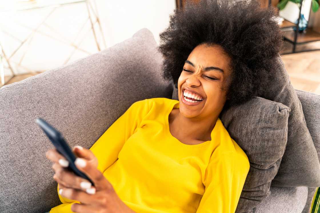 A woman laughing while holding her phone.