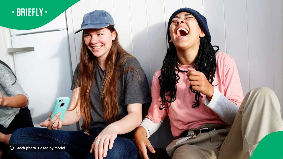 People laughing at content on their phone. People laughing at content on their phone.
