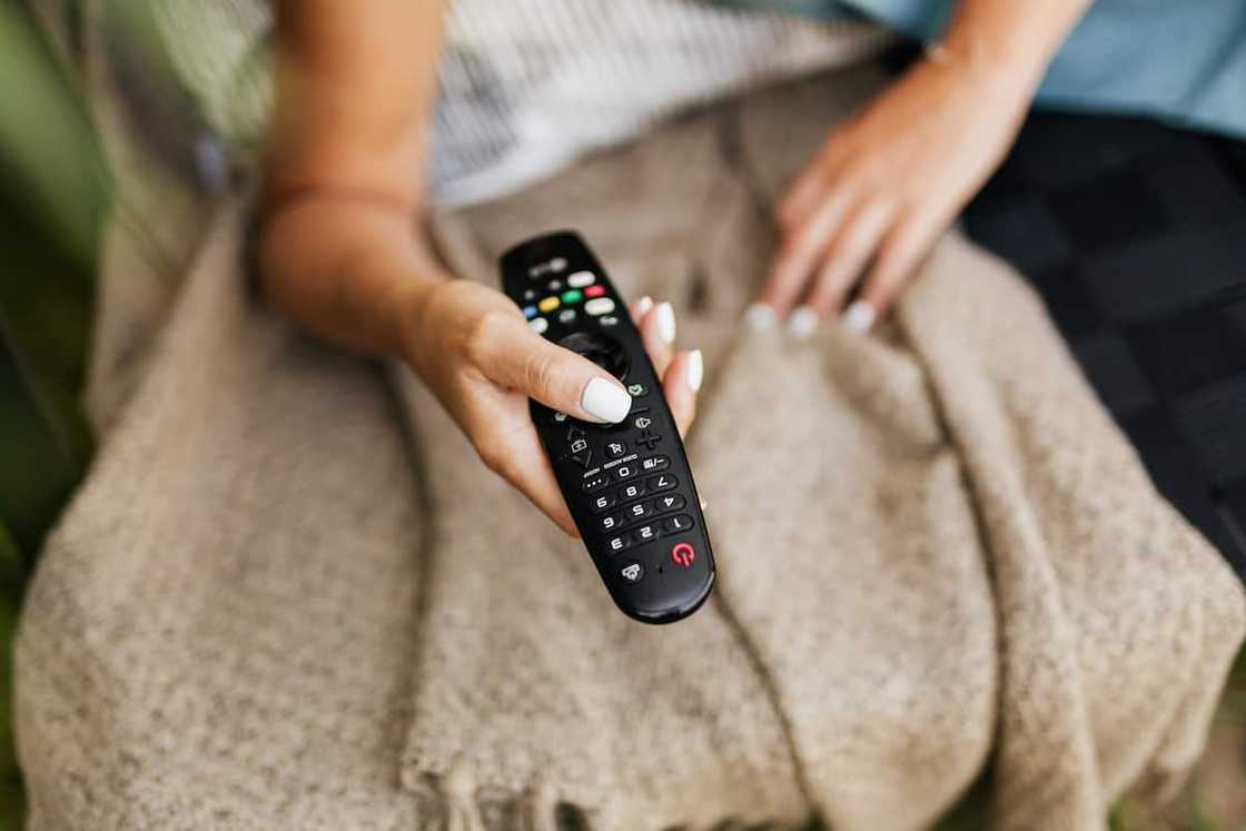 A woman using a DStv remote A woman using a DStv remote