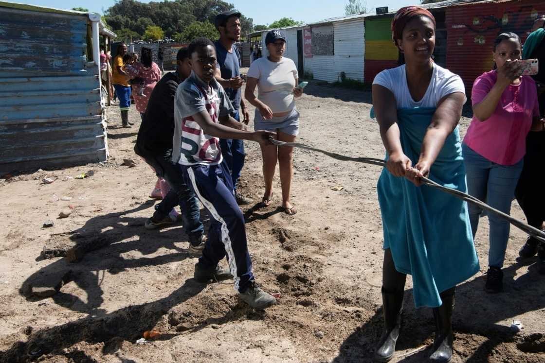 Tug-of-war: residents try to hang on to illegal electricity lines at Oasis Farm near Cape Town Tug-of-war: residents try to hang on to illegal electricity lines at Oasis Farm near Cape Town