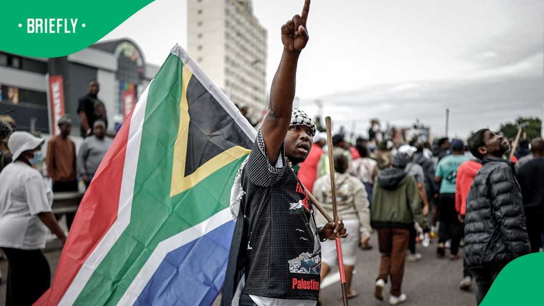 A protester gestures while holding a South African flag as he marches with others during a demonstration by the "March and March" movement marking an unofficial deadline set by citizen-led groups for undocumented foreign nationals to leave South Africa