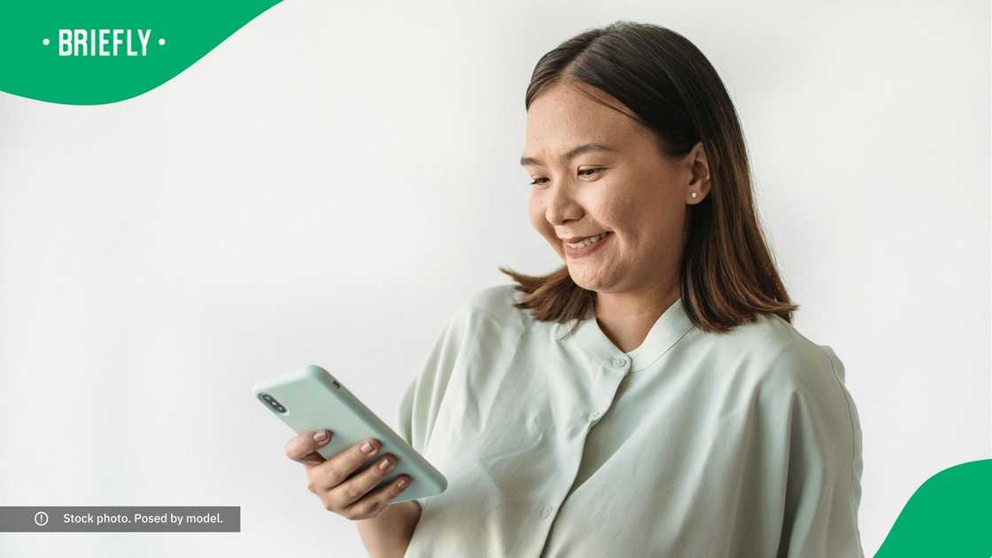 A woman smiling at her phone.