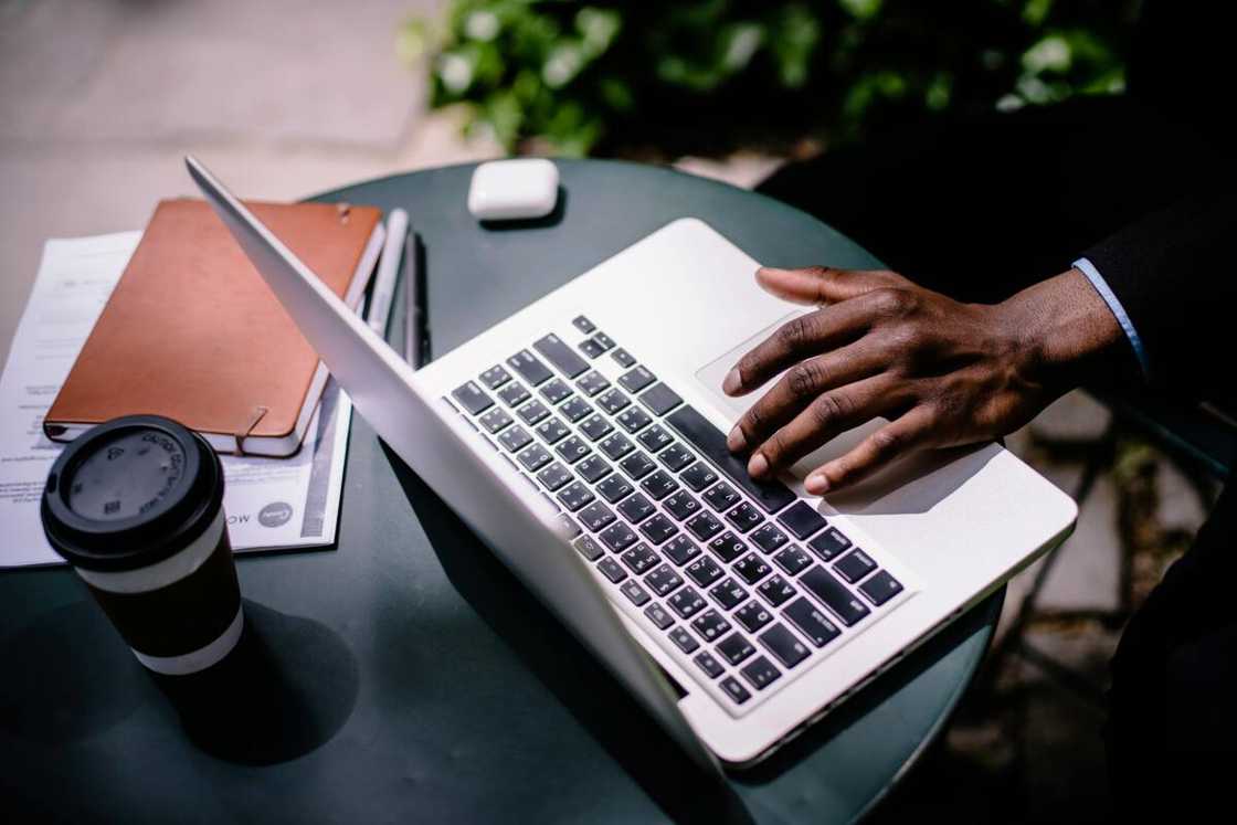 A Black hand is using a laptop on a black desk