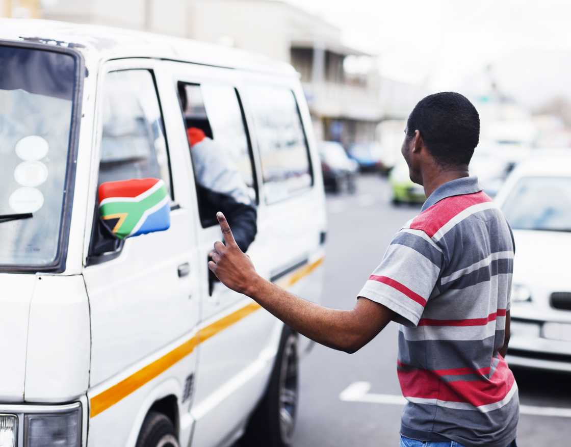 A picture of a Mzansi man pointing for a taxi to stop