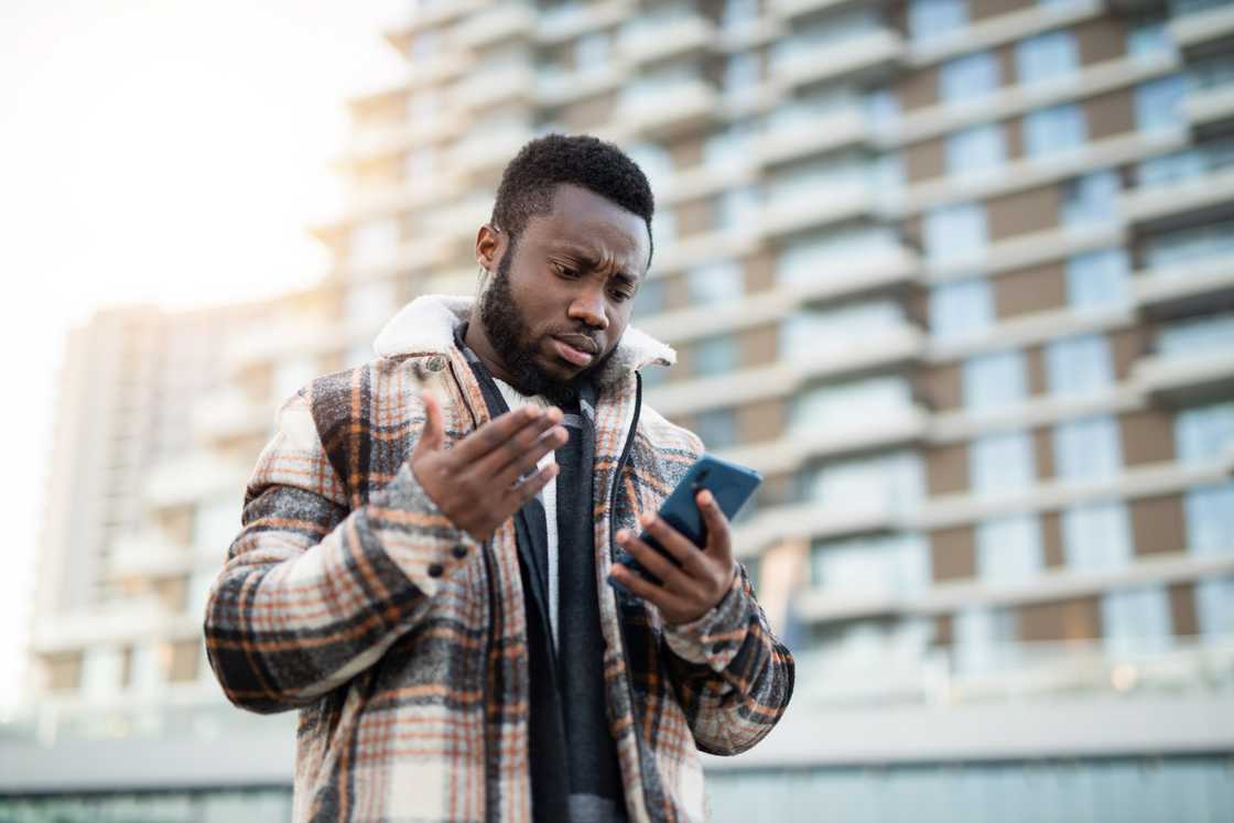 A confused man using his phone. A confused man using his phone.