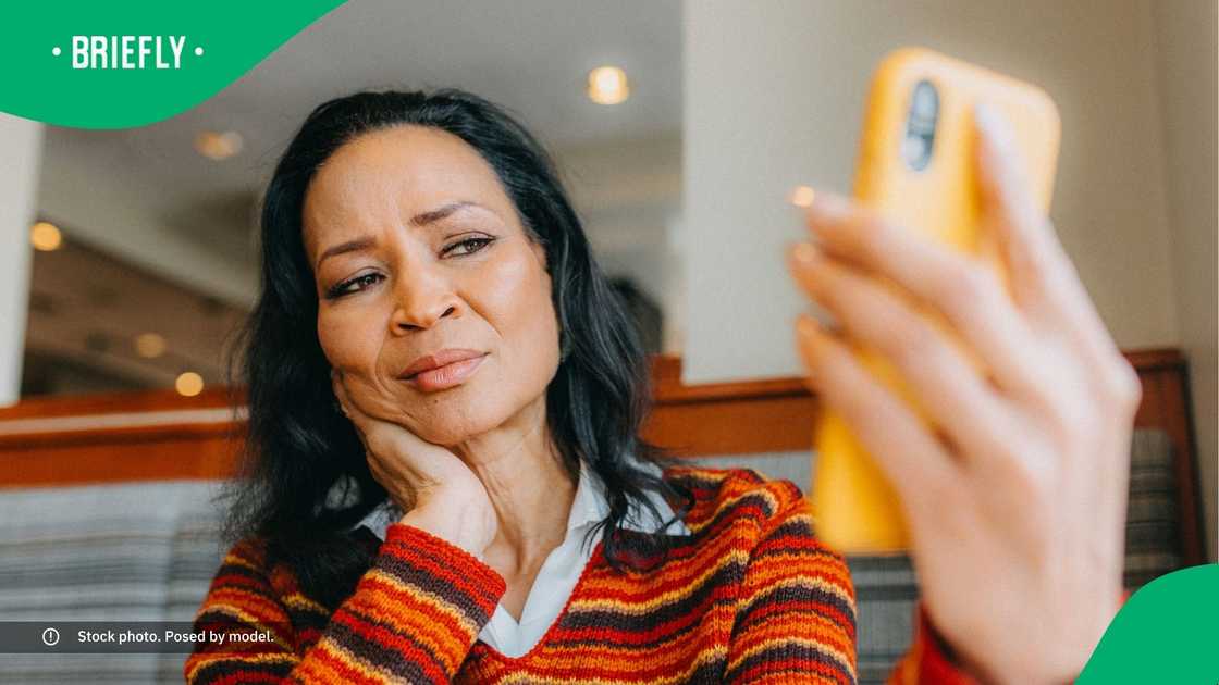 A woman looking at her phone with uncertainty. A woman looking at her phone with uncertainty.