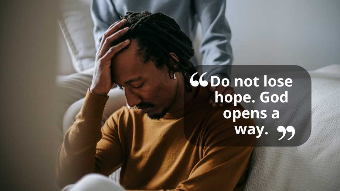 A distressed man sits while someone comforts him. A distressed man sits while someone comforts him.