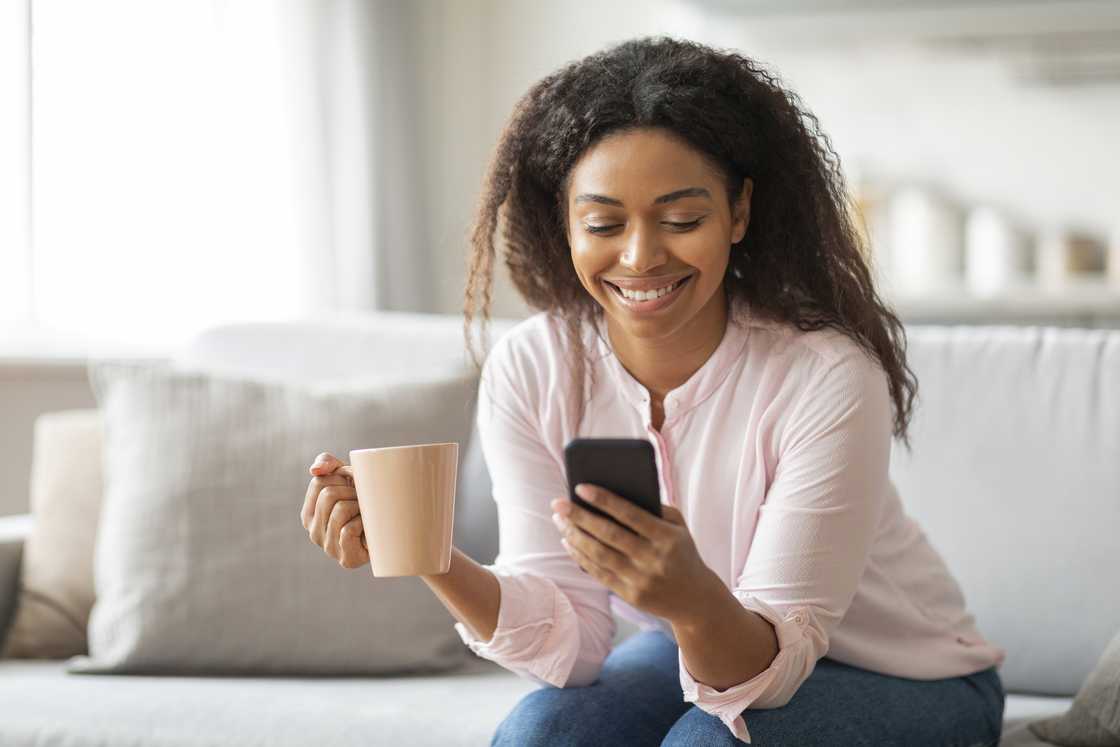 A woman smiles at her phone. A woman smiles at her phone.