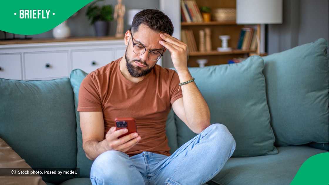A confused man looks at his phone.