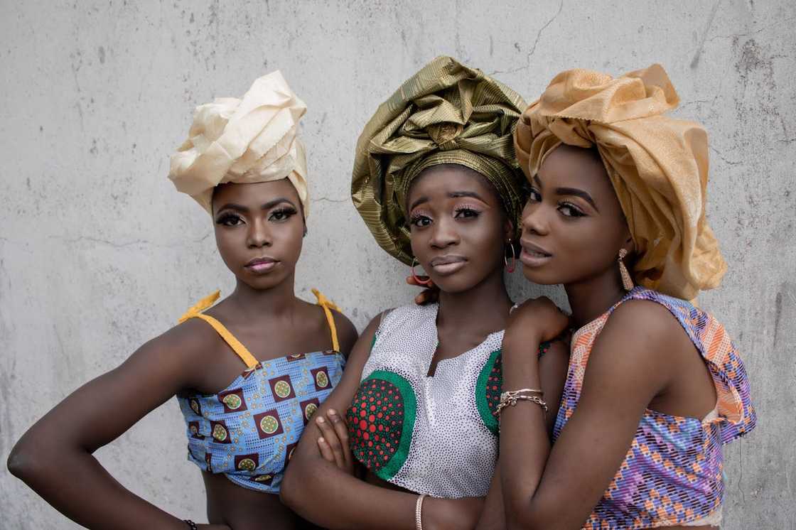 Three women wearing traditional headwraps pose together. Three women wearing traditional headwraps pose together.