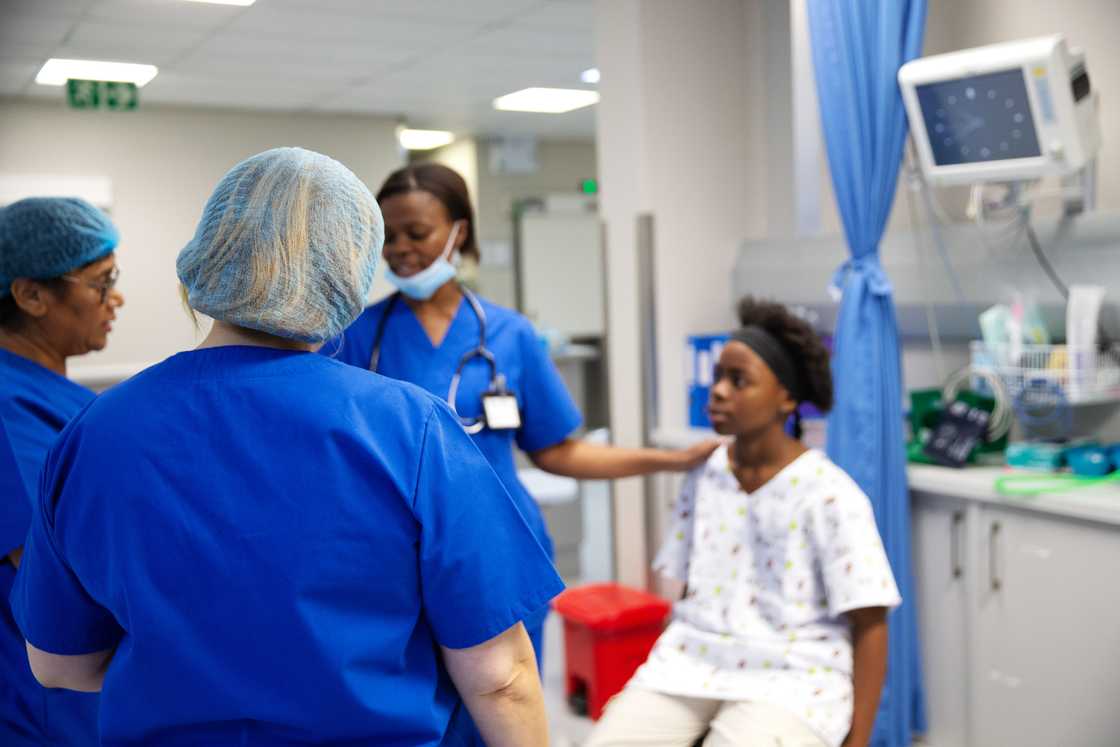Nurses whisper near a worried patient. Nurses whisper near a worried patient.