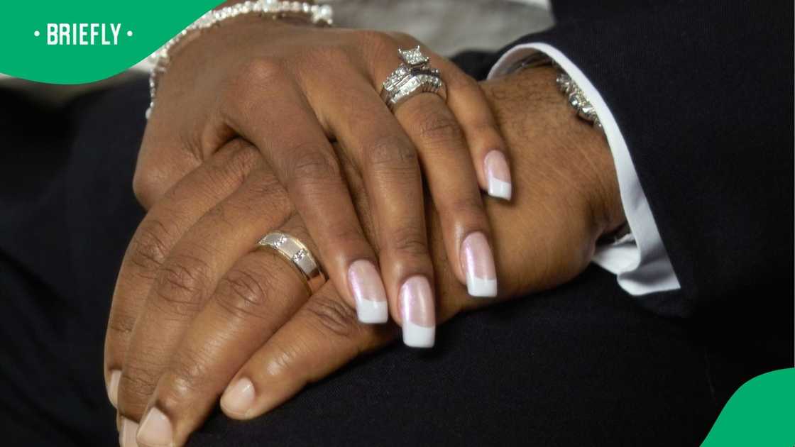 A stock photo of a married couple's hands and wedding rings