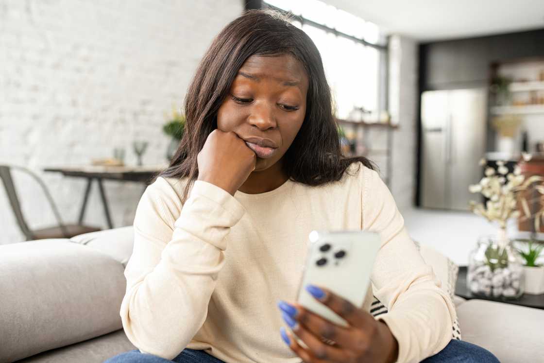 A concerned woman looking at her phone.