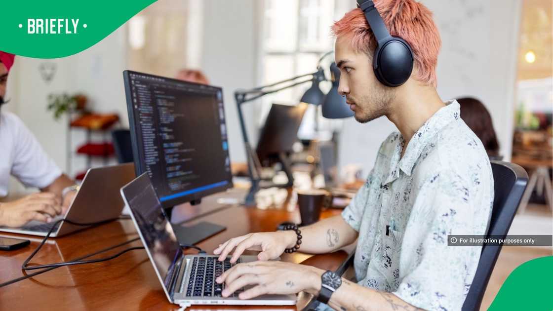 Young IT professional working at coworking office with people working at back Young IT professional working at coworking office with people working at back
