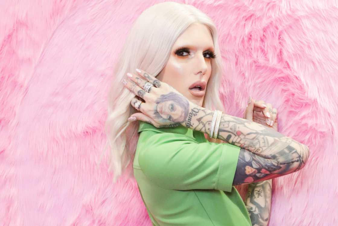 Jeffree Star posing in a green shirt against pink fur background Jeffree Star posing in a green shirt against pink fur background