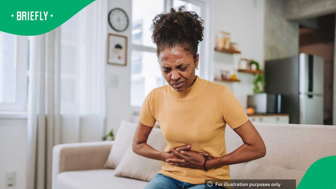A woman clenching her stomach to show symptoms of abdominal pain or diarrhoea A woman clenching her stomach to show symptoms of abdominal pain or diarrhoea