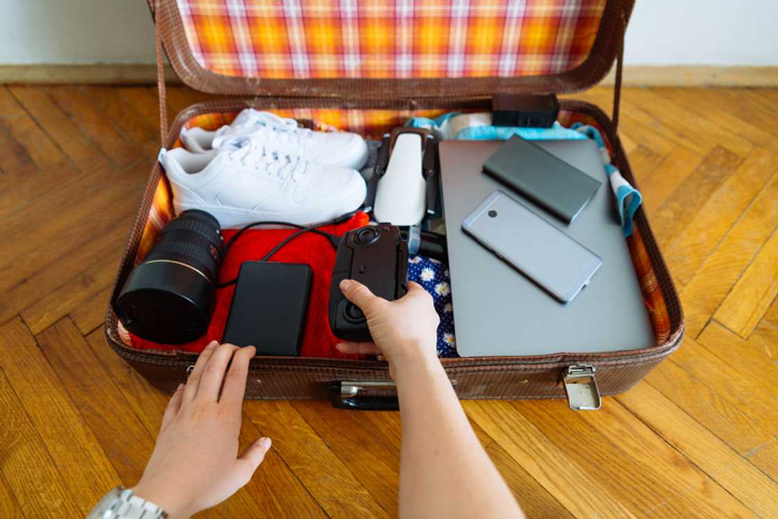 An open luggage filled with summer items, including a laptop