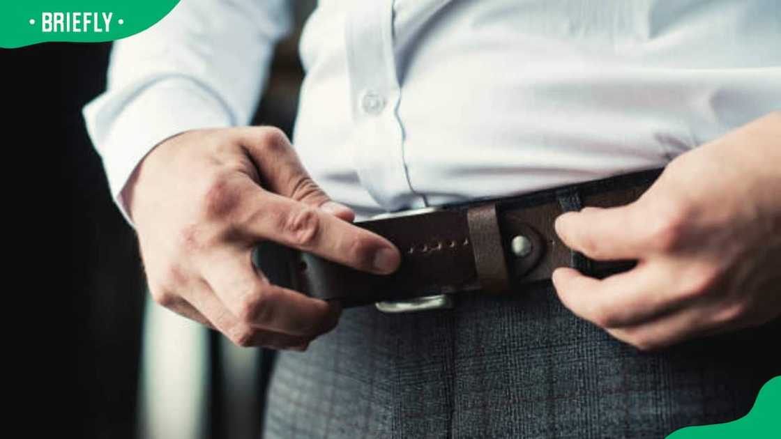 A man in grey slacks and brown belt A man in grey slacks and brown belt
