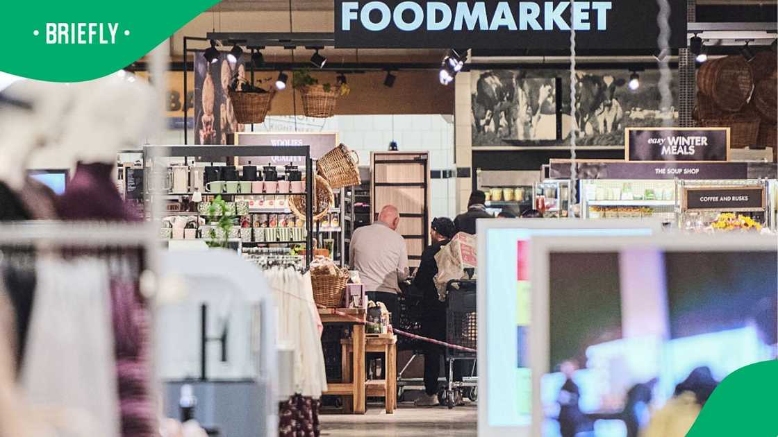 The view looking into the supermarket section showed hanging wicker baskets, merchandise displays, and shoppers pushing grocery trolleys The view looking into the supermarket section showed hanging wicker baskets, merchandise displays, and shoppers pushing grocery trolleys