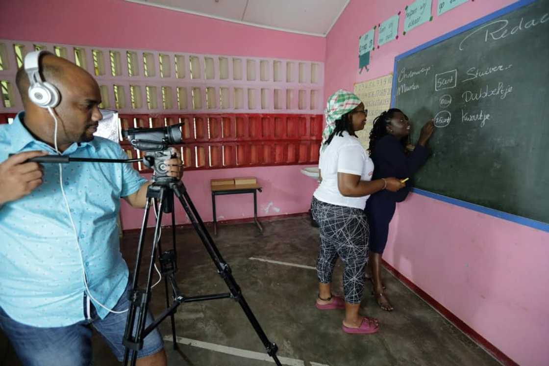 Soulamy Laurens (C) and other villagers who now live in the capital, prepare educational videos for children in flooded areas