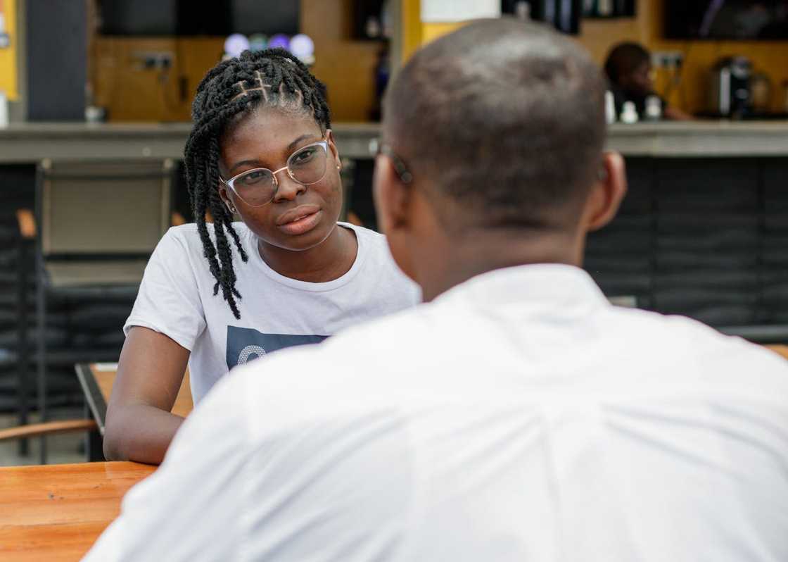 A woman listens intently while sitting across from a man at a table.