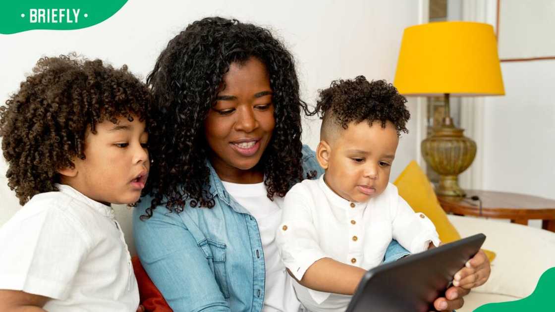 A young African mother using a tablet with her children