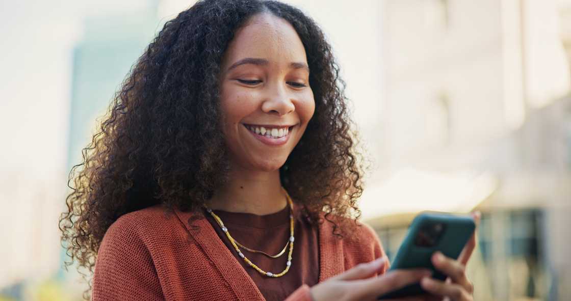 A woman smiling at her phone.