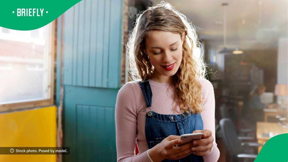 A woman smiling at her phone. A woman smiling at her phone.