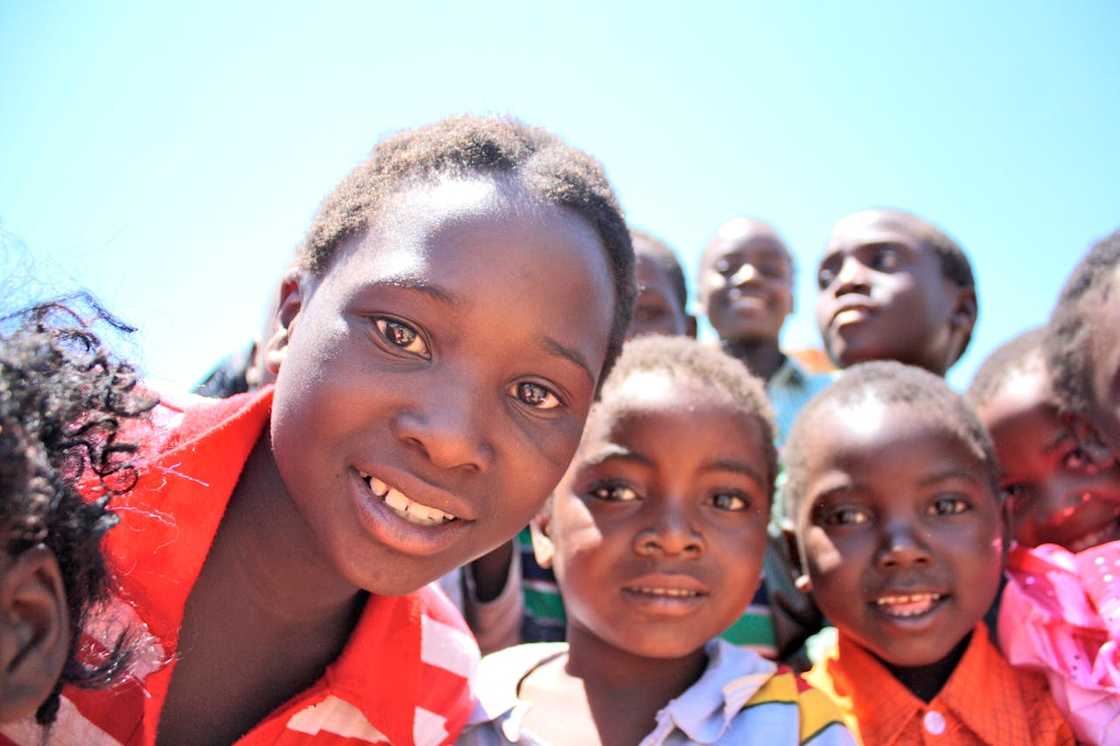 Smiling children gathered outdoors under the bright sky. Smiling children gathered outdoors under the bright sky.