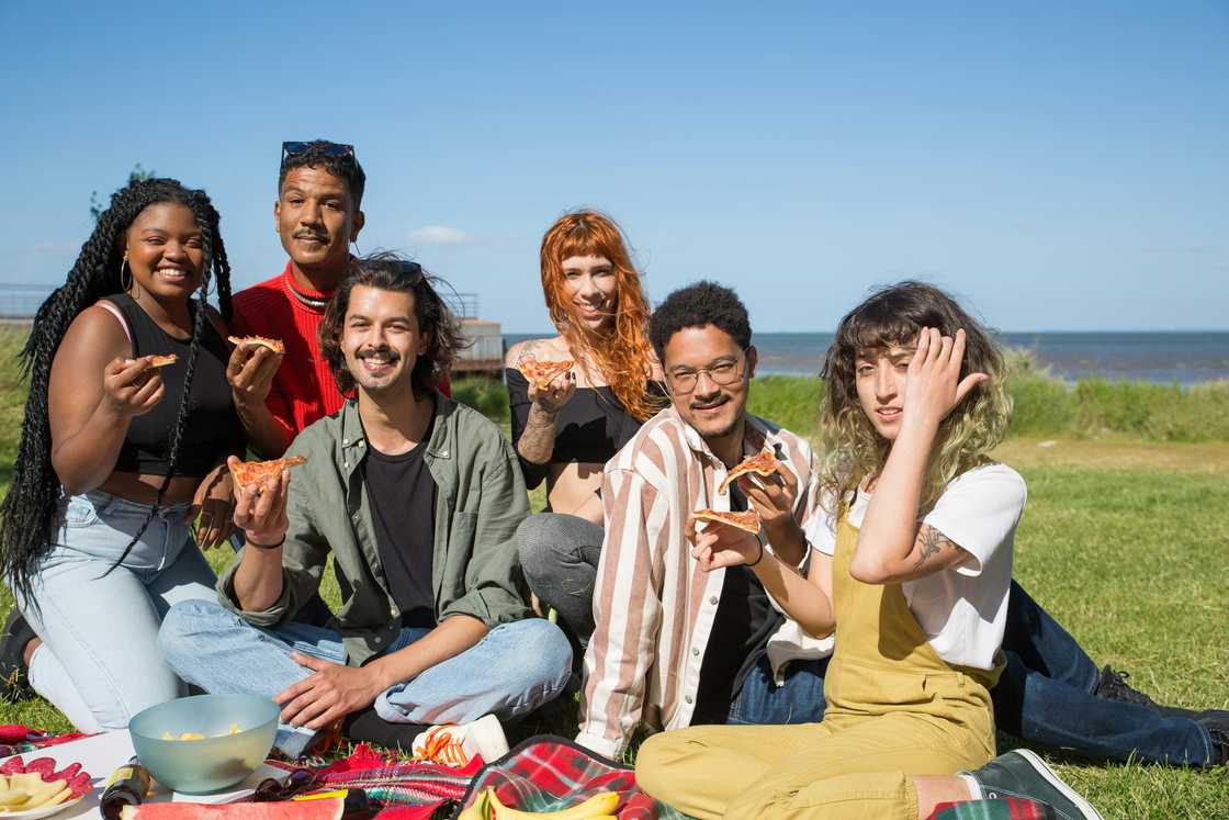 A group of friends enjoying pizza on a picnic