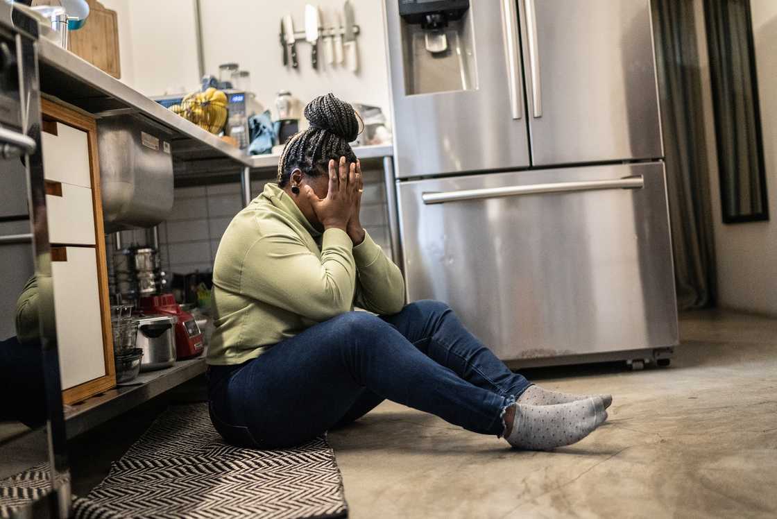 A woman sits sobbing on the kitchen floor. A woman sits sobbing on the kitchen floor.