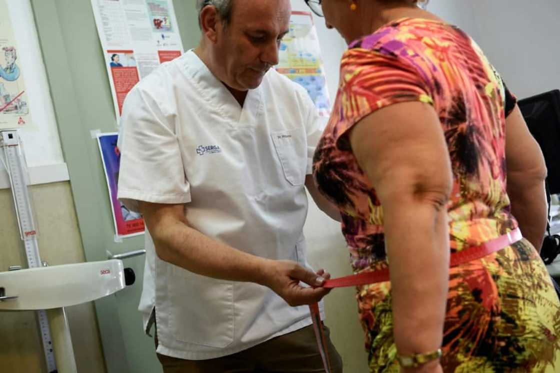 A doctor weighs a woman in Naron, Spain A doctor weighs a woman in Naron, Spain