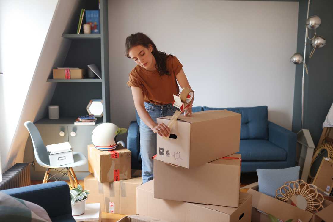 A young woman closed her moving boxes with tape