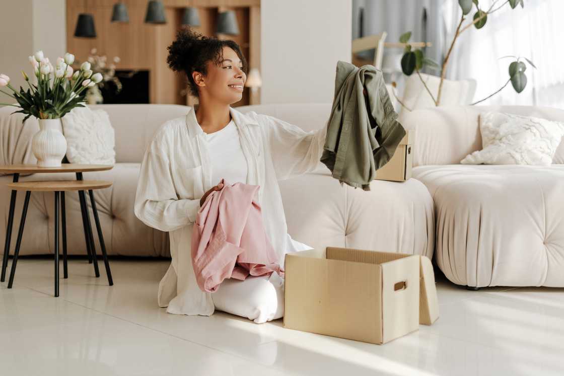 A young woman smiling while unpacking clothes from a cardboard box
