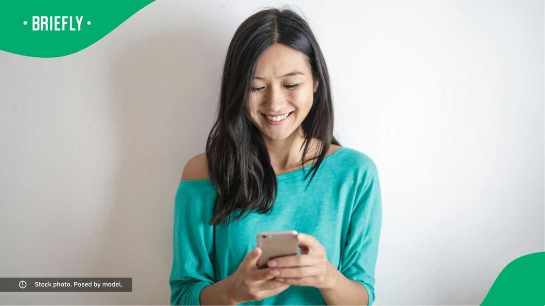 A woman smiling at her phone. A woman smiling at her phone.