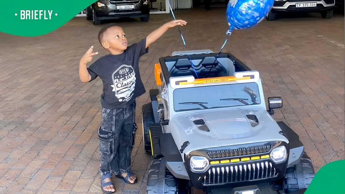 A TikTok photo of boy standing next to a toy car