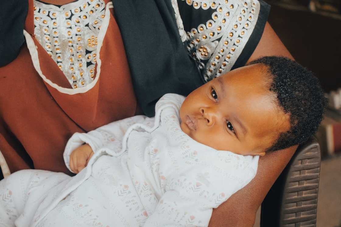 A baby rests in an adult's arm.