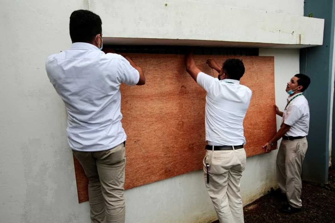 Workers protect the windows of a bank on October 8, 2022 before the arrival of Hurricane Julia in Bluefields, Nicaragua