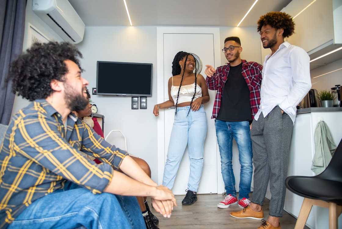 A group of friends laughing and chatting together in a modern living space.