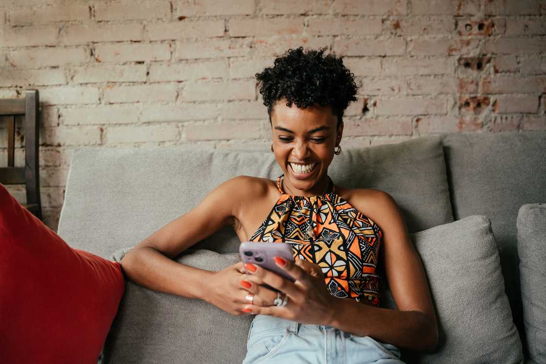 A woman laughing at her phone.