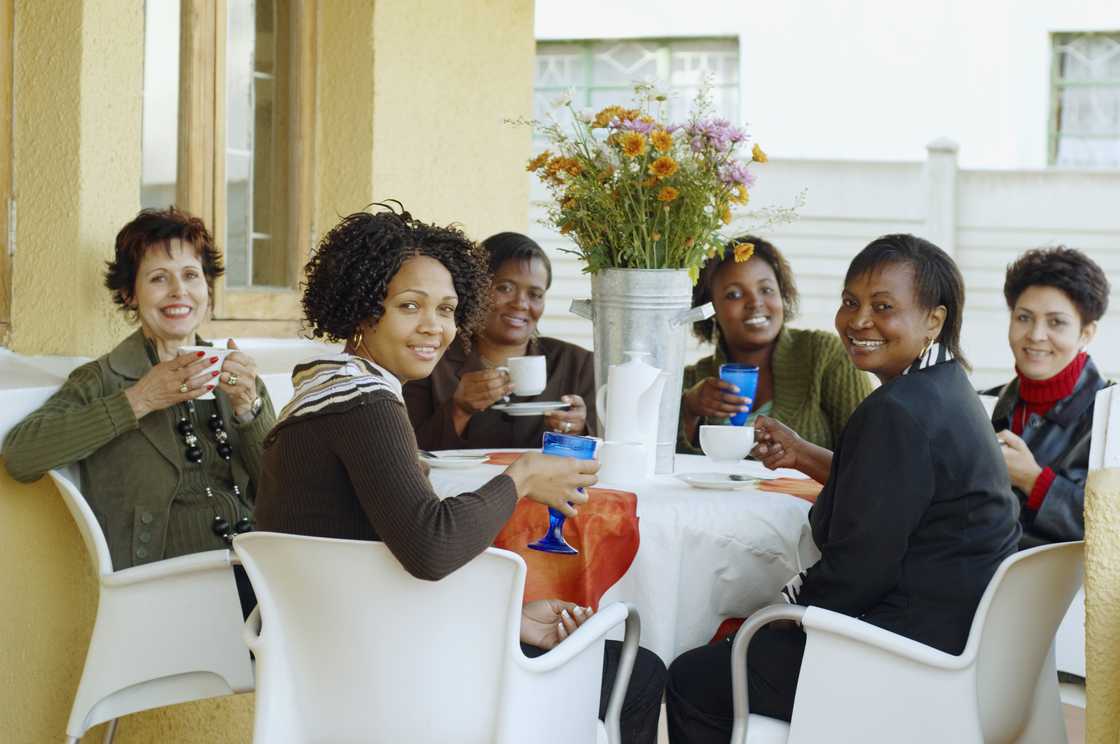 Women gathered in a community hall for a stokvel meeting.