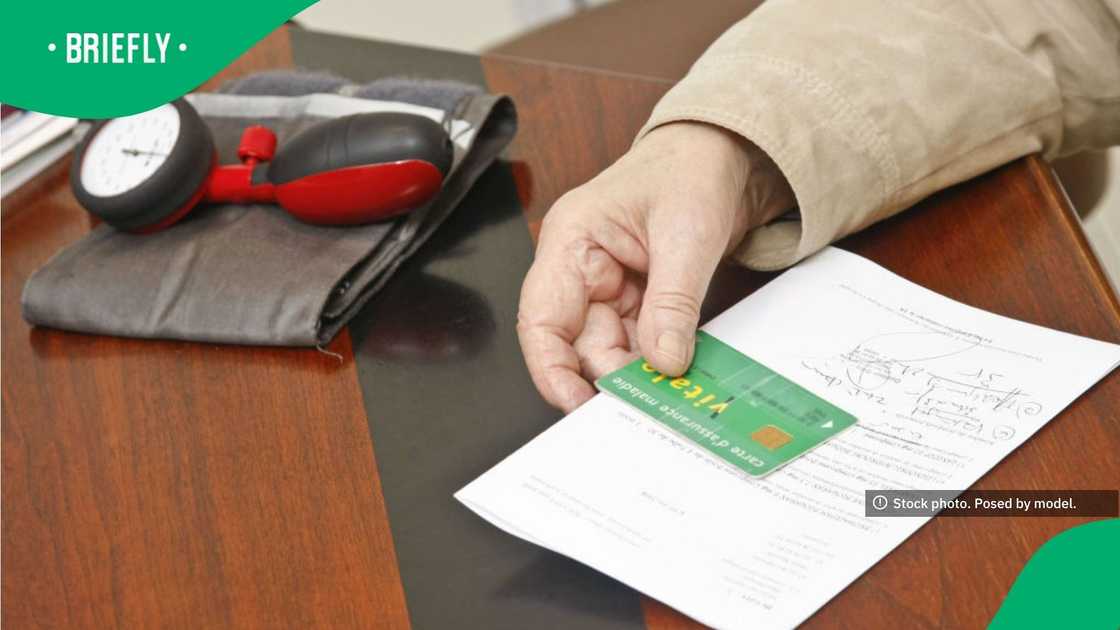 The stock image captured a patient presenting their health insurance card along with paperwork during a medical consultation The stock image captured a patient presenting their health insurance card along with paperwork during a medical consultation