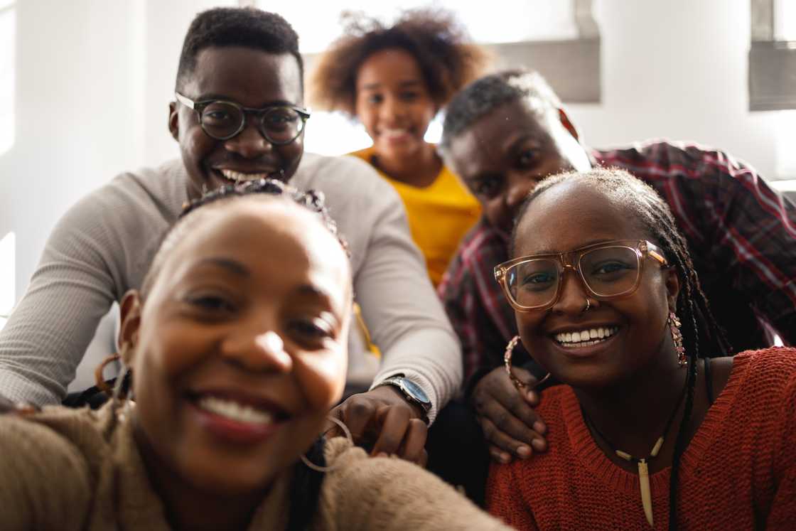Five people, including one child, gather indoors for a selfie.