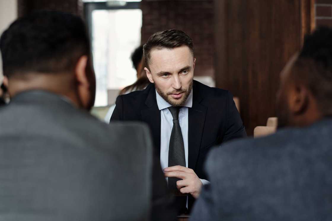 A businessman speaks seriously to two people during a meeting. A businessman speaks seriously to two people during a meeting.