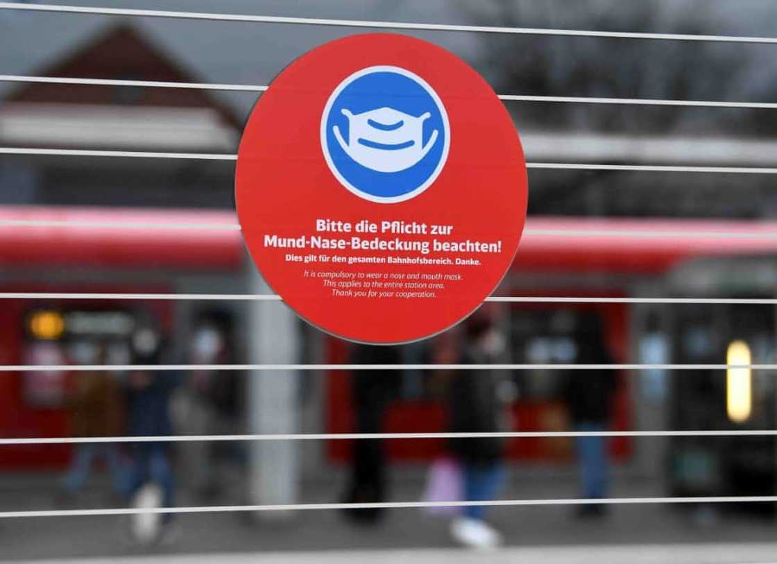 A sign informs people to cover their mouth and nose with a face mask on a train platform in Munich A sign informs people to cover their mouth and nose with a face mask on a train platform in Munich