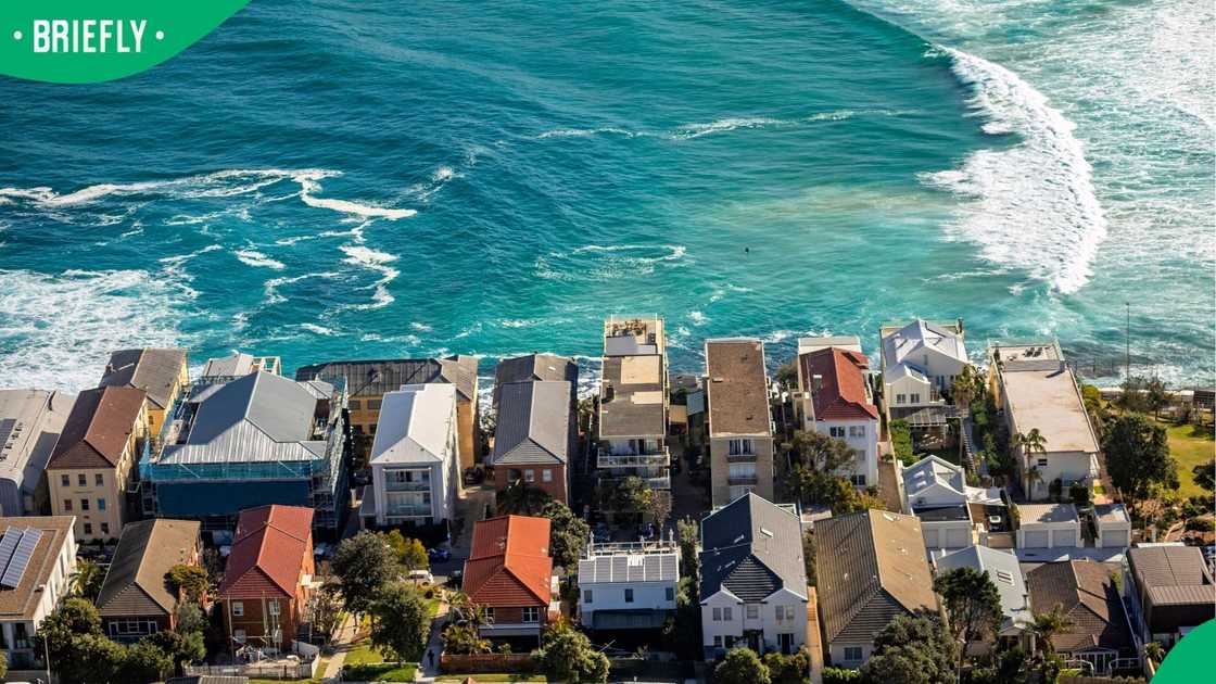 Aerial photography of houses and apartments on coastline with ocean, surf, waves.