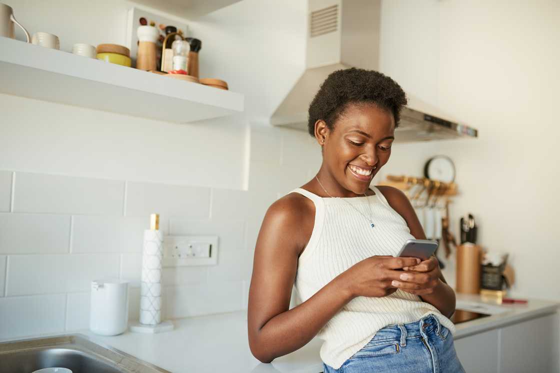 A woman smiling at her phone.